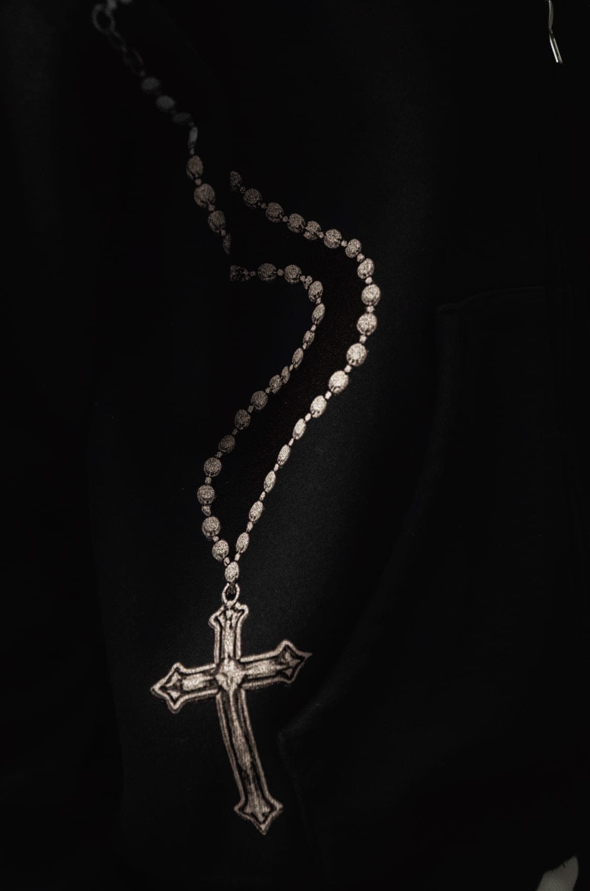 Close detail of rosary beads printed over the hoodie pocket